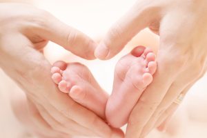 Baby-feet-in-mother-hands-Tin-58846898