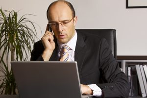 Businessman in suit sitting at desk in office engaged in work on Businessman-in-suit-sitting-at-19498115